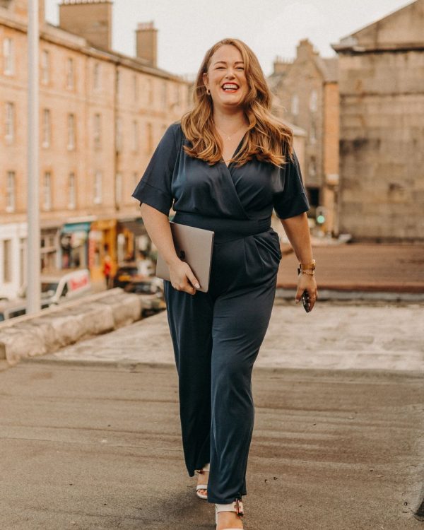 Digital Marketing Consultant & SEO Specialist Aoibhinn Cullen from The OG Marketing Agency walking & laughing on a rooftop in Edinburgh with her laptop