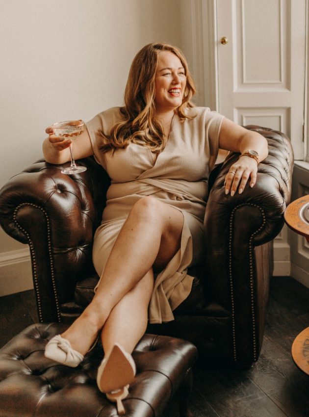 Digital Marketing Consultant & SEO Specialist Aoibhinn Cullen from The OG Marketing Agency sits in a leather chair with champagne in her hand